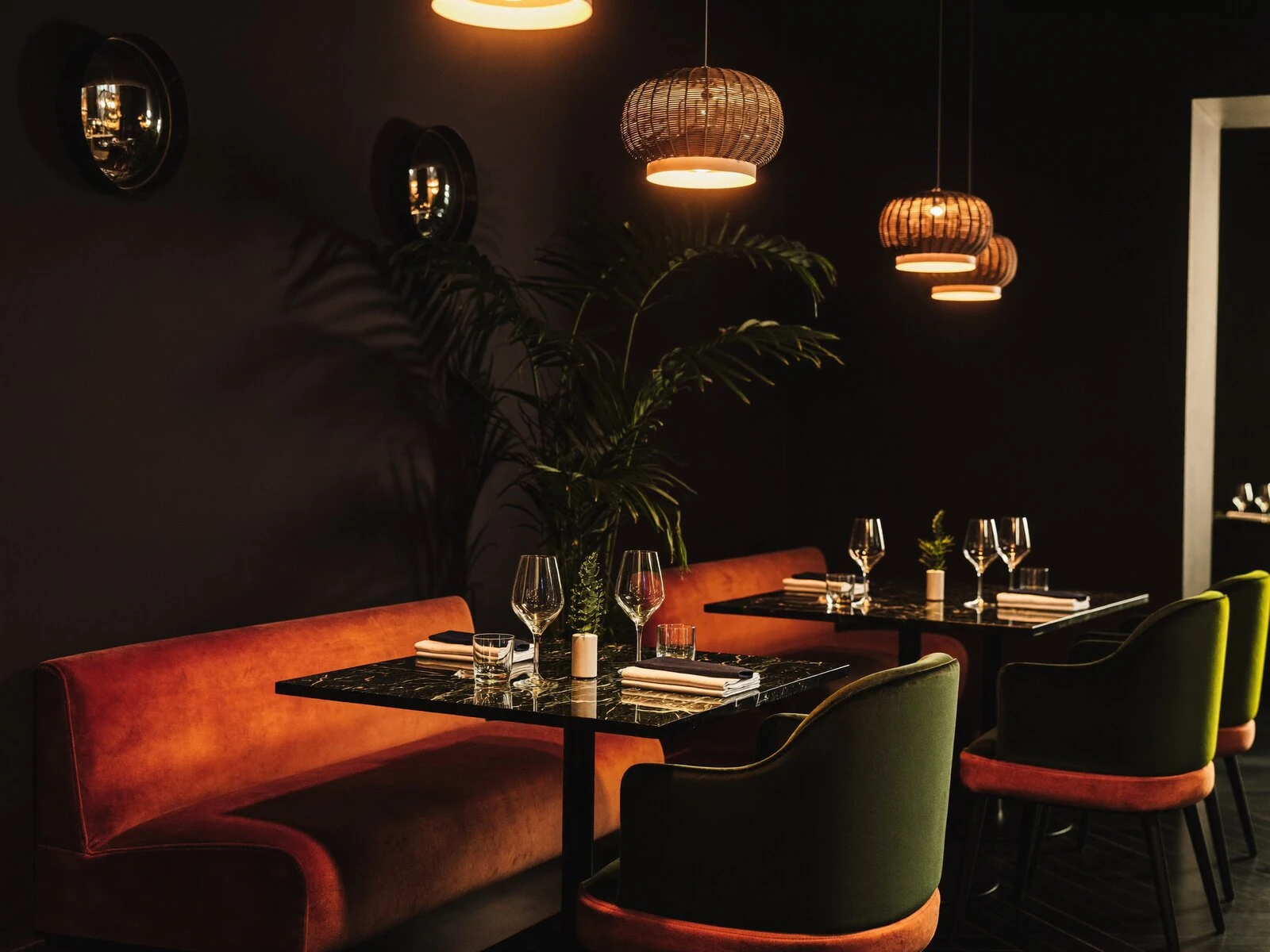 Warm, dimly lit interior of Hajia 1 with velvet booth seating and rattan pendant lights