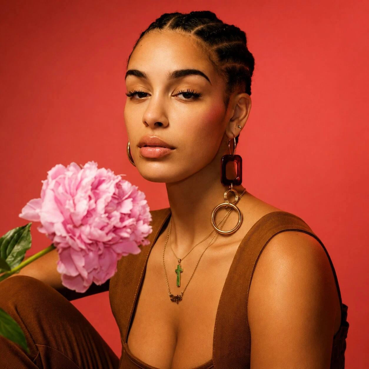 Jorja Smith holding a pink peony against a red backdrop